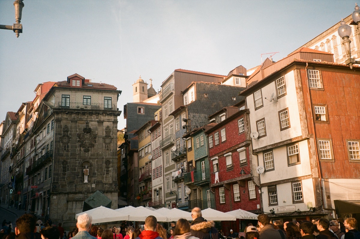 A crowd of people walking down a street next to tall buildings