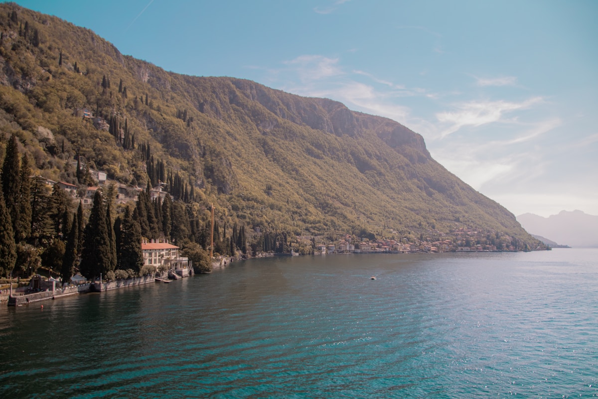 A serene lake with a forested mountain backdrop.